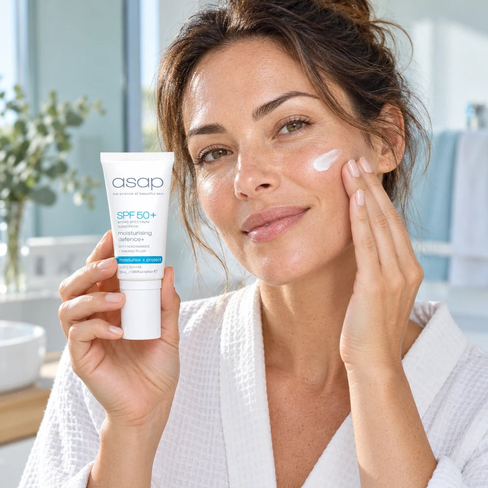 Vrouw brengt ASAP Moisturising Defence+ SPF50+ aan op haar wang, 50ml tube in de hand
